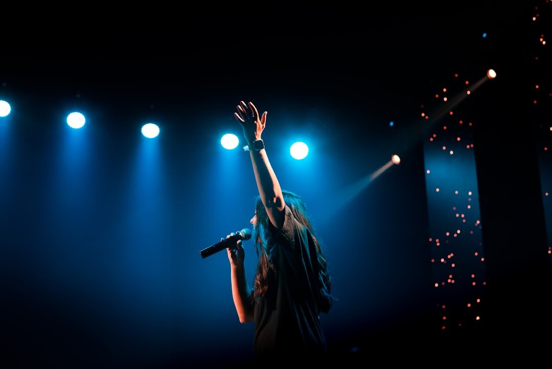 Singer performing on a concert stage with colorful lights